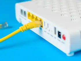 Żółty kabel sieciowy podłączony do portu LAN routera i modemu.